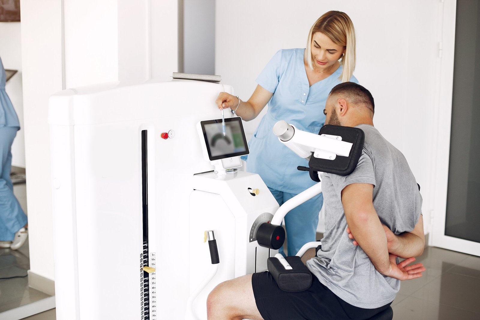 Patient has a rehabilitation in physiotherapy clinic.  A therapist helps him. People are in the gym.